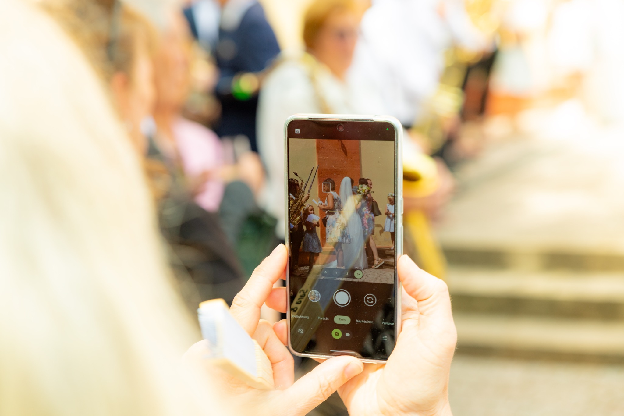 Eine Person fotografiert mit dem Smartphone eine Hochzeitsszene